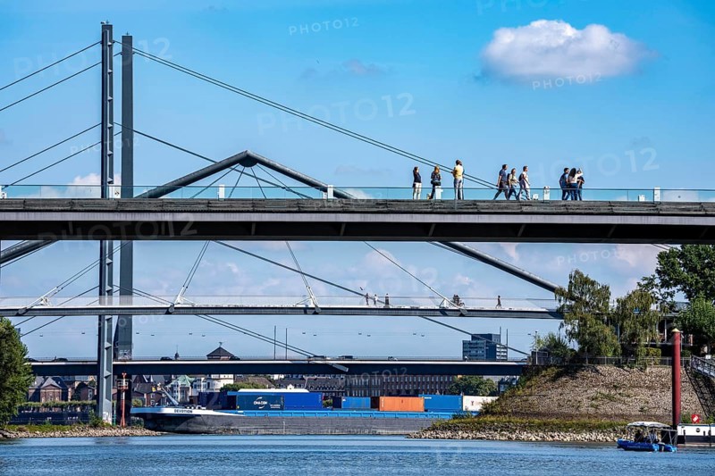 Bridges in Düsseldorf, in the foreground, the pedestrian and cycle bridge over the canal to the inner harbour, media harbour of Düsseldorf, behind it the Rheinknie bridge, road bridge over the Rhine near Düsseldorf, cargo ship, Germany