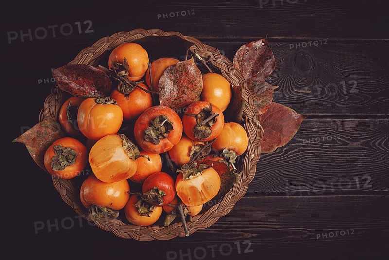 Fresh persimmon in a basket, with leaves, top view, no people