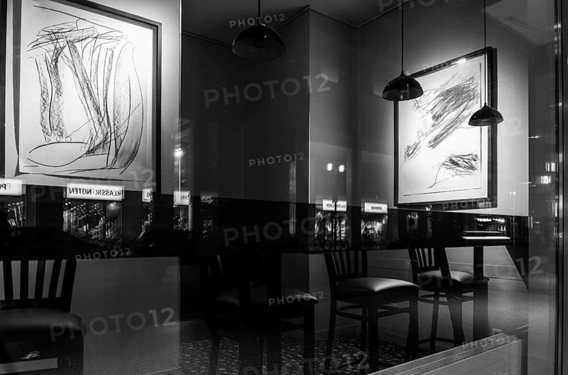 Black and white photograph, urban scene in the evening with reflections of Friedrichstraße in the window pane of a bistro, Berlin, Germany