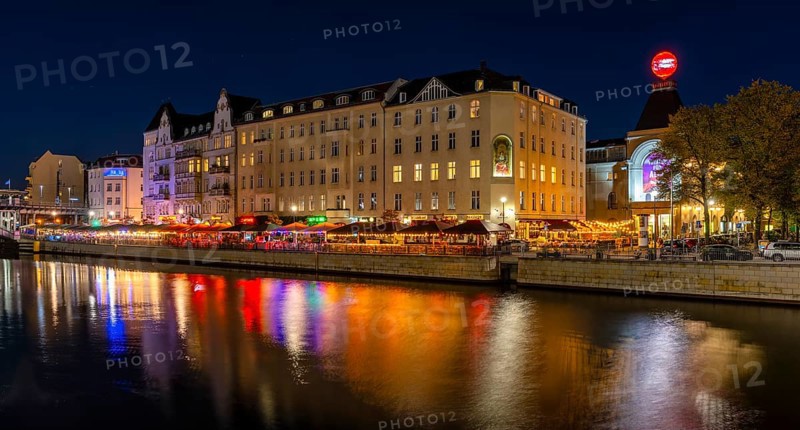 Night photo on the banks of the Spree opposite the Schiffbauerdamm, urban environment with scene locations at the Berliner Ensemble theatre, reflections of the night lighting appear in the water of the Spree, Berlin, Germany