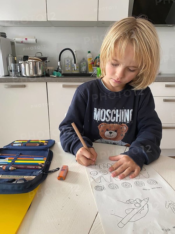 Boy, 6 years old, blond, 1st grade, practises holding the pen correctly, does homework in the kitchen, pencil case, Stuttgart, Baden-Württemberg, Germany
