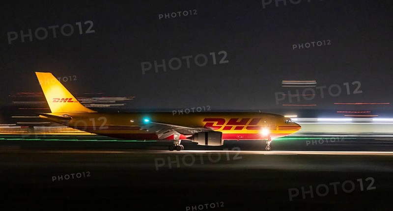 Stuttgart Airport in the early morning. DHL cargo plane landing. Light traces with motion blur. Stuttgart, Baden-Württemberg, Germany
