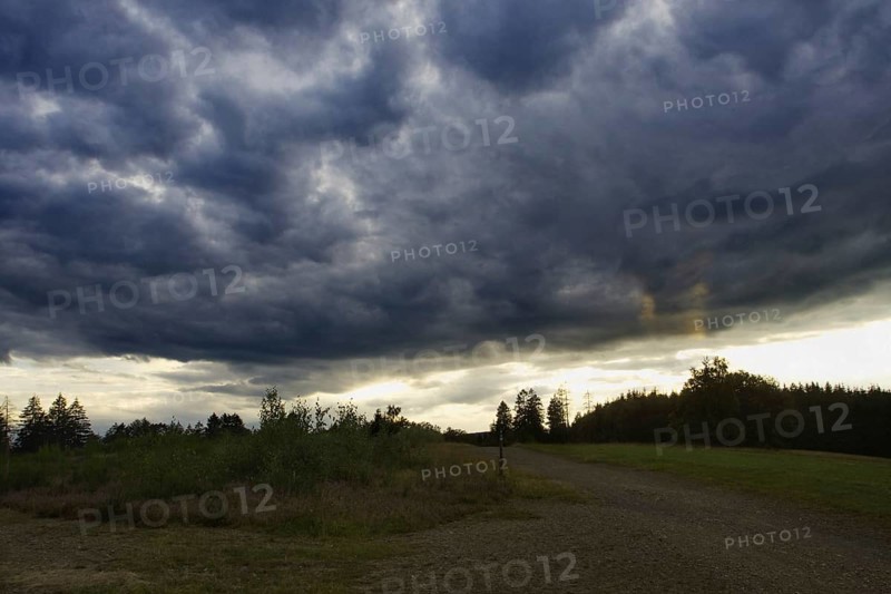 Dramatic, dark clouds drift across a landscape at dusk. Heaths and rough grassland nature reserve near Trupbach, Siegen