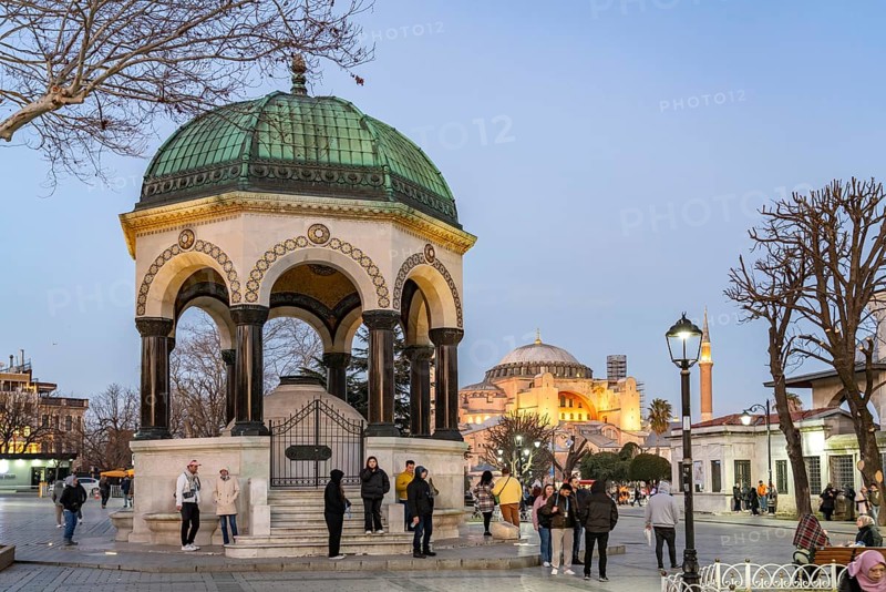 Tourists at the German Fountain or Kaiser Wilhelm Fountain and the Hagia Sophia at dusk, Istanbul, Turkey