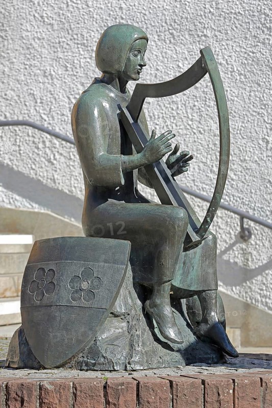 Sculpture Minnesänger von Wissenlo by the sculptor Hatto Zeidler 1978, monument, bronze sculpture, seated harp player with city coat of arms, musician with harp playing music, seated, coat of arms shield, Unterer Markt, Wiesloch, Baden-Württemberg, Germany