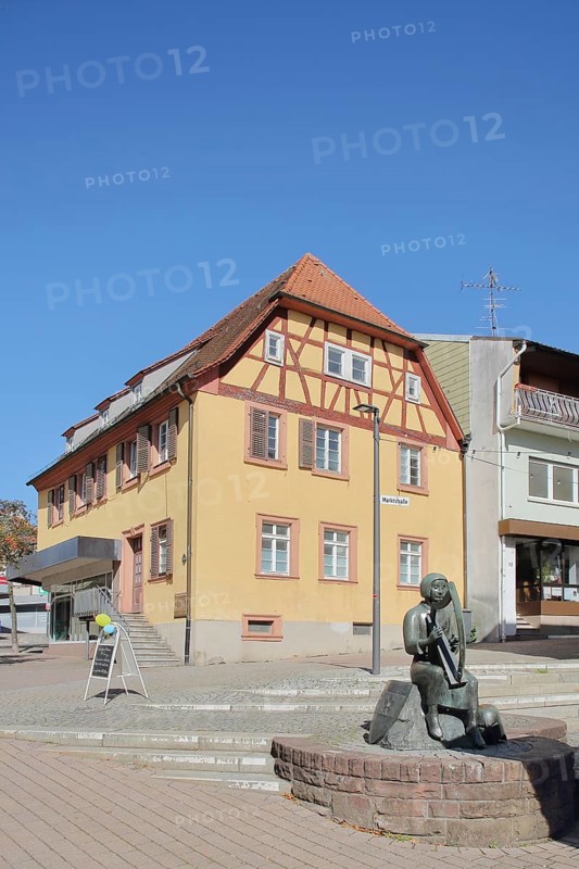 Sculpture Minnesänger von Wissenlo by the sculptor Hatto Zeidler 1978 and Bronner House, monument, bronze sculpture, seated harp player with town coat of arms, musician with harp playing music, seated, coat of arms shield, Unterer Markt, Wiesloch, Baden-Württemberg, Germany
