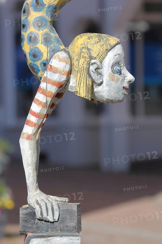 Sculpture Die Literaturnerin by Hans Scheib 2007, Modern Art, Girl figure doing a handstand on a pile of books with striped clothes, acrobatic, standing on her head, wood sculpture, detail, Adenauerplatz, Wiesloch, Baden-Württemberg, Germany
