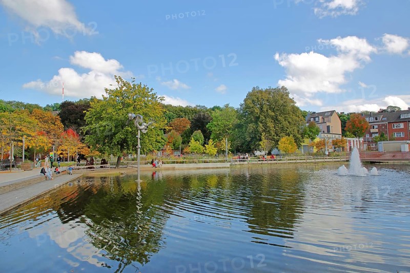 Bastinsweiher with sculpture, seating, bench, people, pedestrians, park, pond, autumn colours, fountain, water jet, Rhineland, Stolberg, North Rhine-Westphalia, Germany