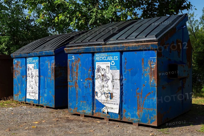 Blue metal with black plastic lid industrial size recycling bins for depositing glass, metal and plastic containers in, Ile des Moulins, Old Terrebonne, Quebec, Canada