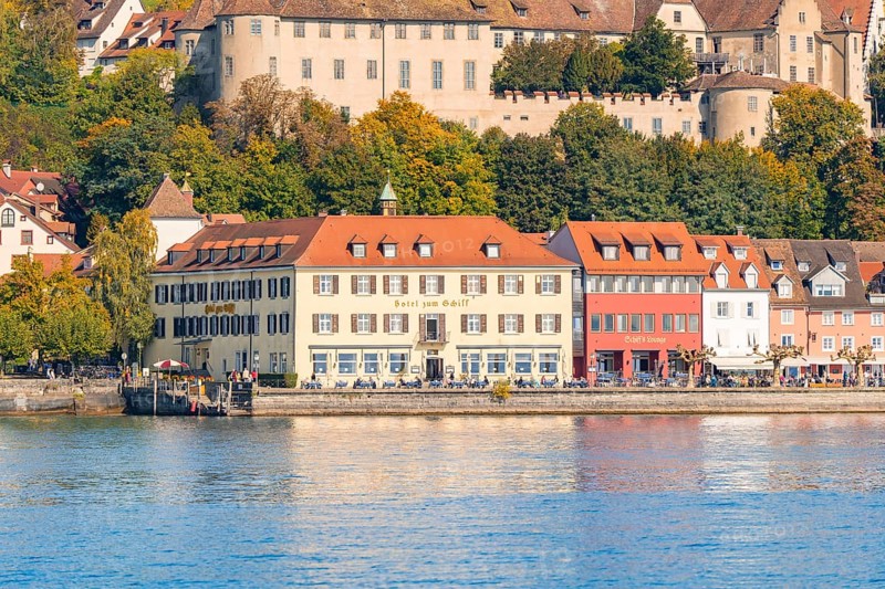 Historic buildings on the lakeshore with autumnal vegetation in the background, Meersburg, Lake Constance, Germany