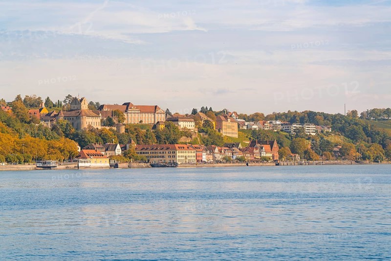 Town view on the lakeshore with historic buildings and autumnal trees under a blue sky, Meersburg, Lake Constance, Germany