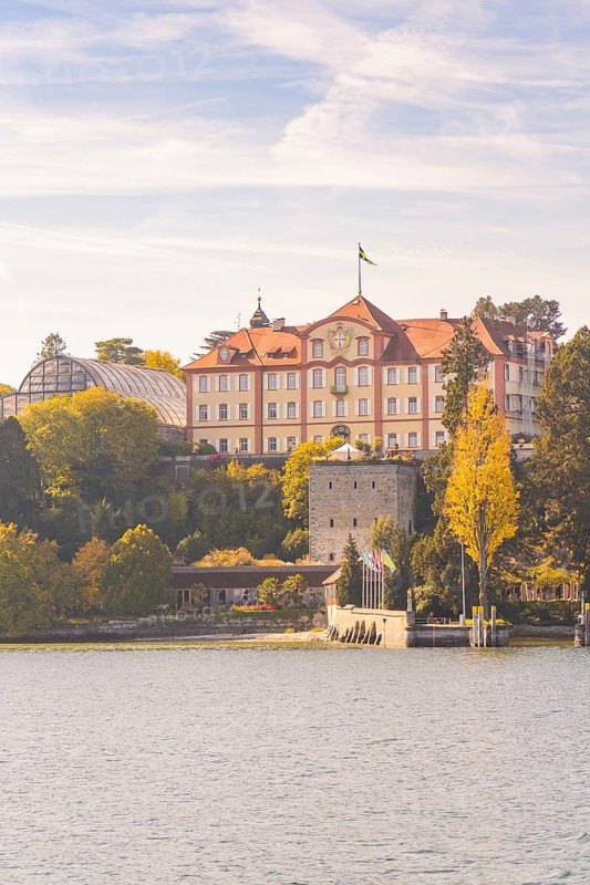 Historic castle on the lake with autumn trees and cloudy sky, Mainau Island, Lake Constance, Germany