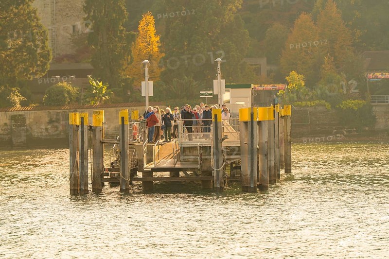 Group of people gathering on a jetty in sunny autumn weather, Mainau Island, Lake Constance, Germany