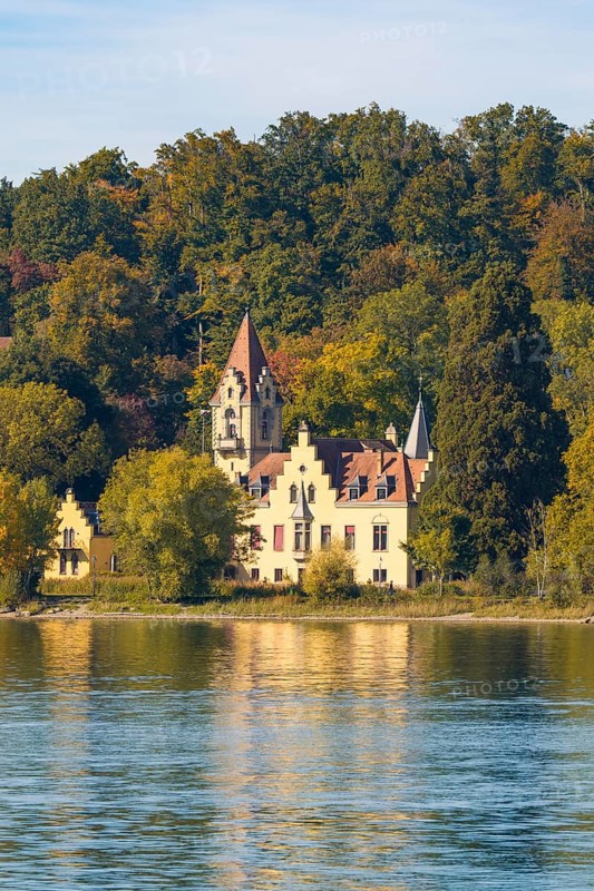 A historic manor house nestled in autumnal trees on the shore of a tranquil lake, Constance, Lake Constance, Germany