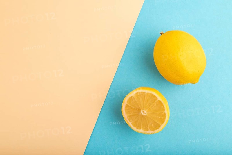 Yellow Lemon Cut in half on orange and blue pastel paper background. Top view, flat lay, copy space. healthy food, vegetable, minimalism