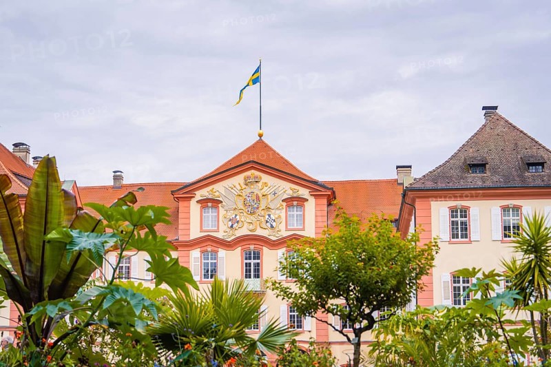 Historic building with a flag and plants in the garden, Mainau flower island, Lake Constance, Germany