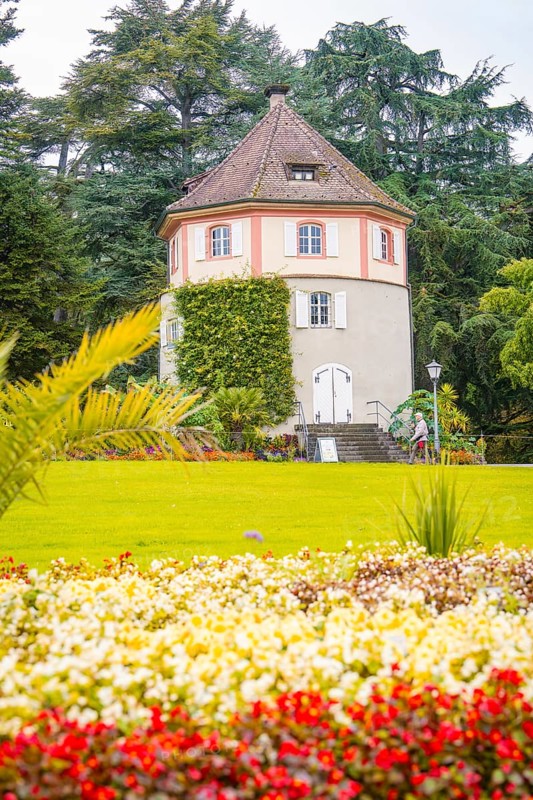 Round tower in the garden, surrounded by blooming flowers, Mainau flower island, Lake Constance, Germany