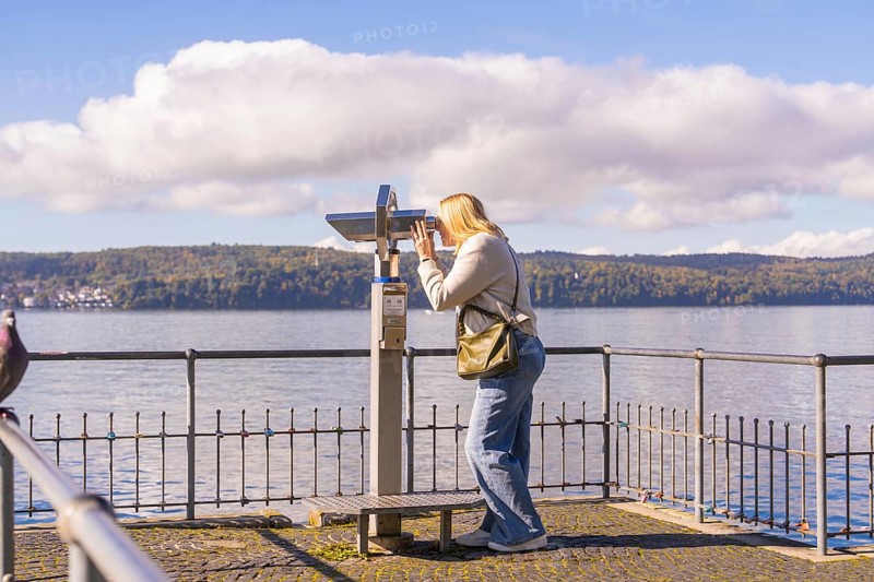 Woman using binoculars to look out over the lake from a platform, Überlingen, Lake Constance, Germany