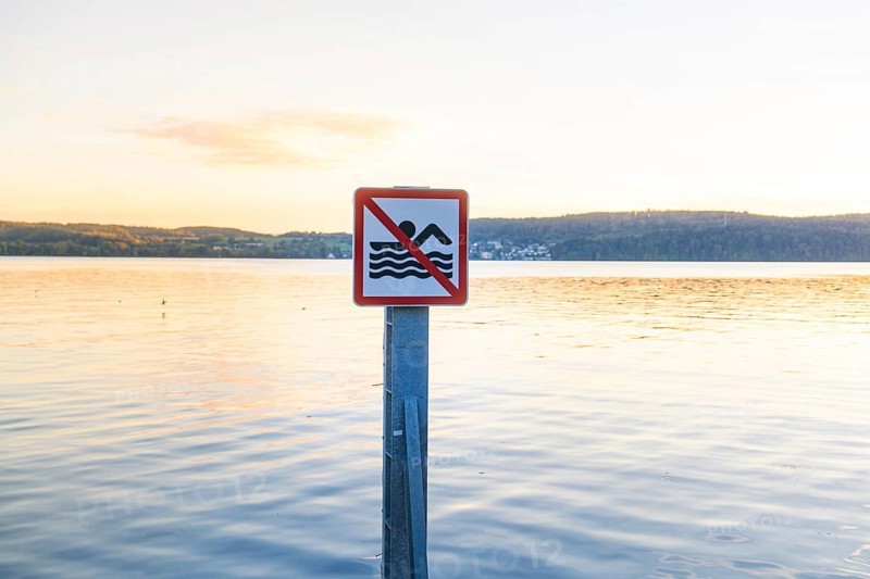 Non-swimmer sign in a calm water landscape at sunset, Überlingen, Lake Constance, Germany