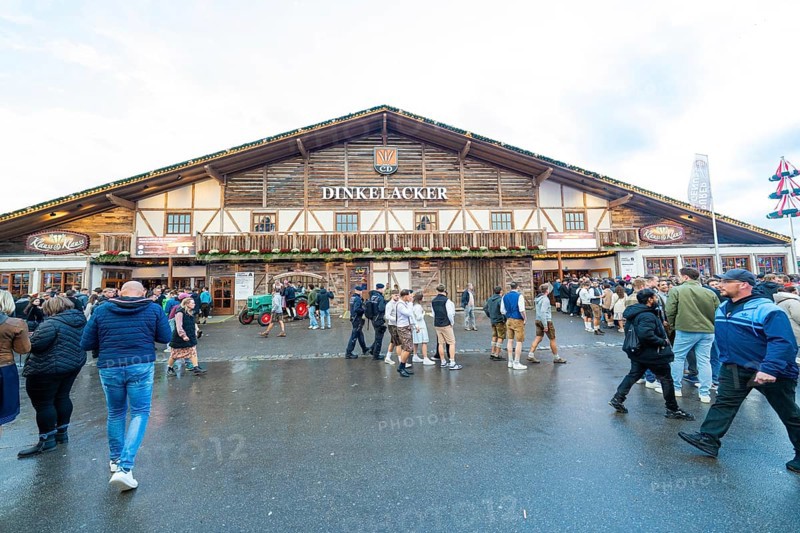 Visitors move in front of a large wooden building, lively atmosphere, Cannstatter Wasen folk festival, Stuttgart, Germany