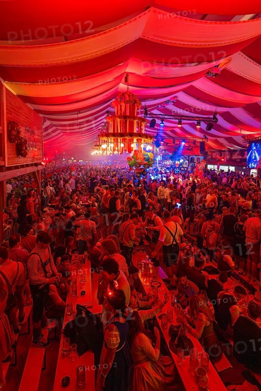 Lively celebration with intense red lighting in a marquee, Cannstatter Wasen folk festival, Stuttgart, Germany