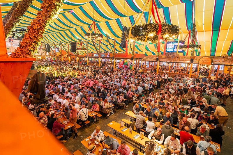 Large crowd celebrating in a colourfully decorated marquee, Cannstatter Wasen folk festival, Stuttgart, Germany