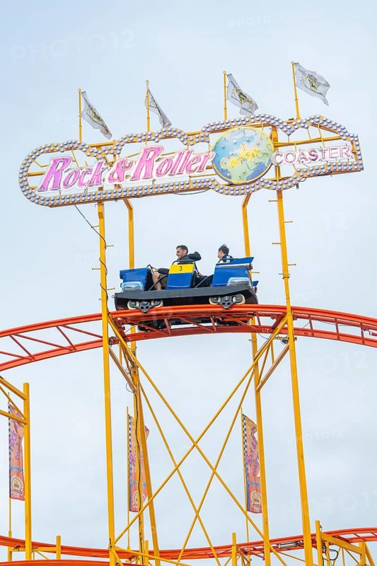 Roller coaster car on rails with rock and roller lettering and colourful flags, Cannstatter Wasen folk festival, Stuttgart, Germany