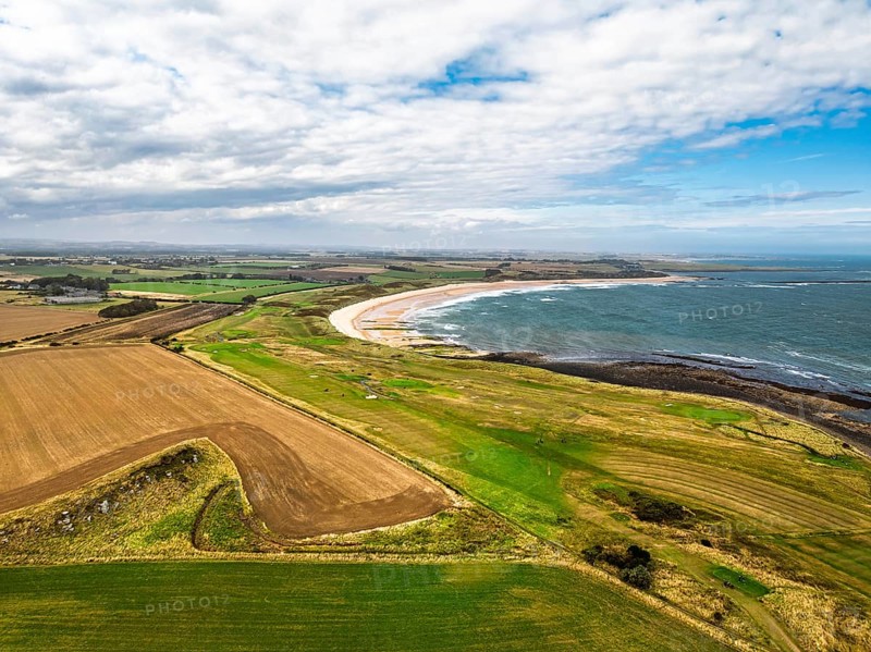 Fields and Farms over Dunstanburgh Castle from a drone, Northumberland Coast, England, United Kingdom