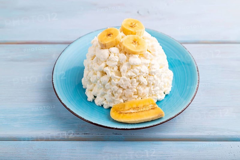 White ?ottage cheese, Curd, with Banana on blue wooden background, side view, close up