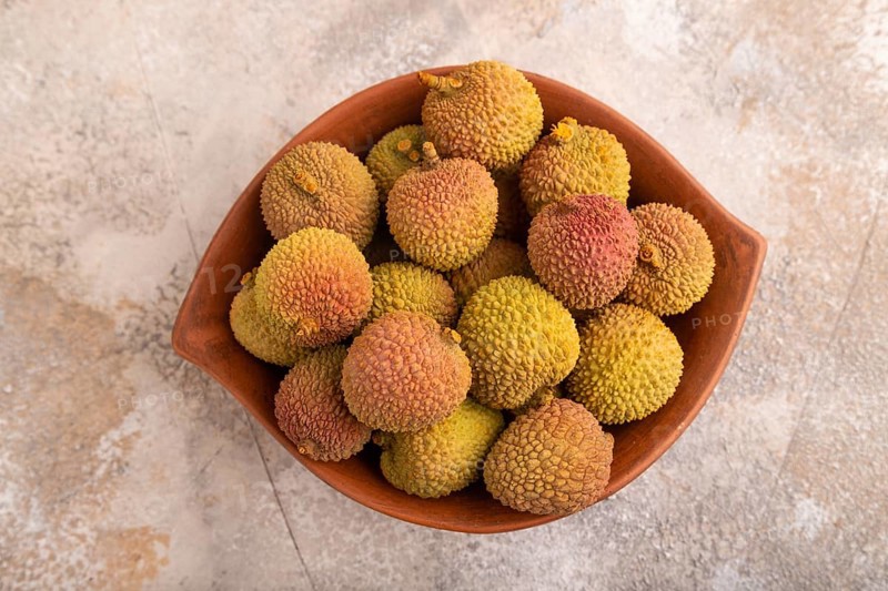 Ripe Lychee on clay bowl on brown concrete background, top view, flat lay, close up, minimalism