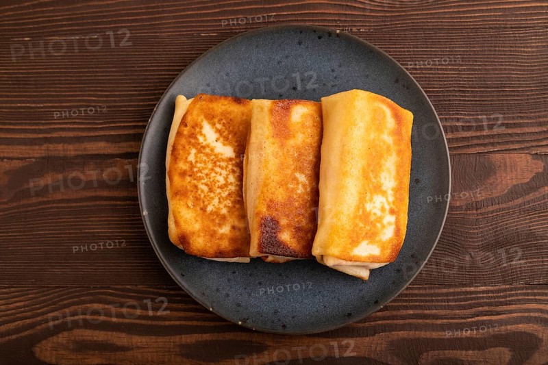Fried crispy pancakes with meat and cheese on brown wooden background. top view, flat lay, copy space