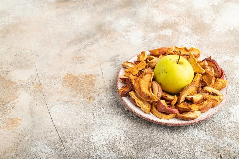 Dried Apples in ceramic bowl on brown concrete background. Side view, copy space, flat lay. healthy food, minimalism. sweet