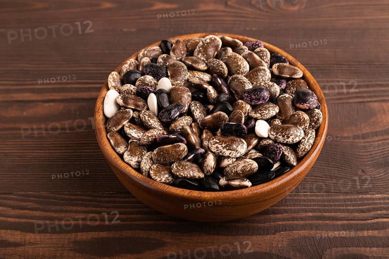Wooden bowl with Kidney beans on brown wooden background, side view, close up, minimalism