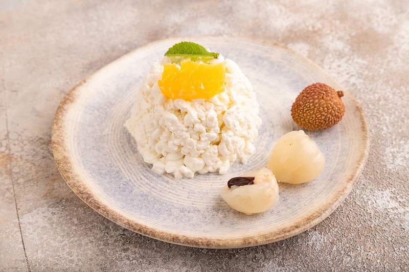 White ?ottage cheese, Curd, with orange and lychee on brown concrete background, side view, close up
