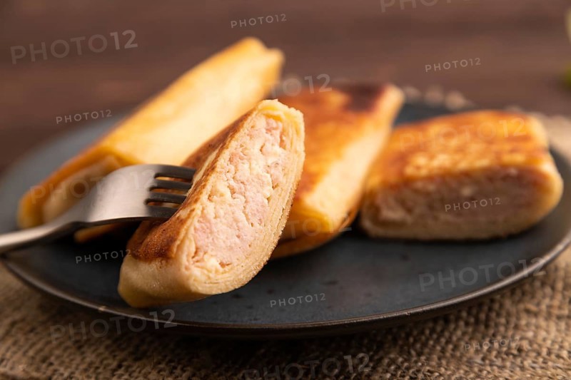 Fried crispy pancakes with meat and cheese on brown wooden background and linen textile. side view, close up, selective focus