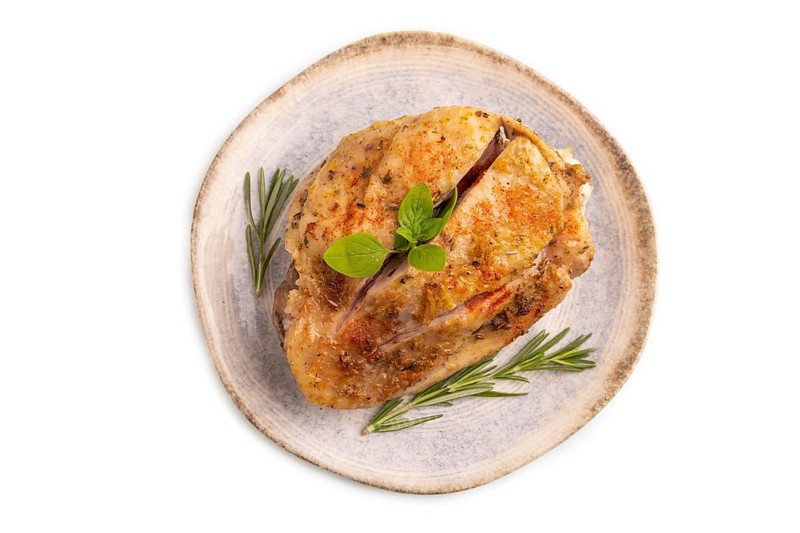 Fried Turkey Thigh with spices and rosemary on plate isolated on white background. top view, flat lay, close up