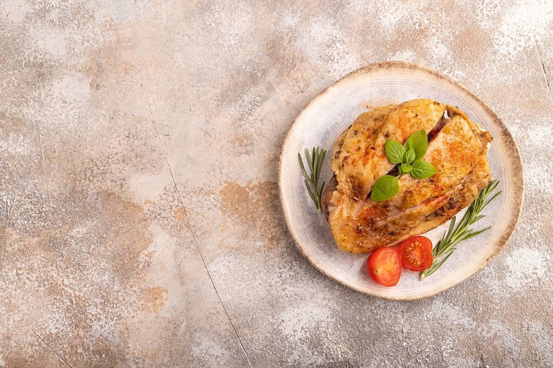 Fried Turkey Thigh with spices and rosemary on plate on brown concrete background. top view, flat lay, copy space