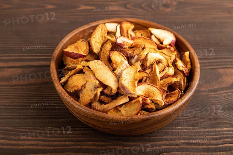 Dried Apples in wooden bowl on brown wooden background. Side view, close up, healthy food, minimalism. sweet