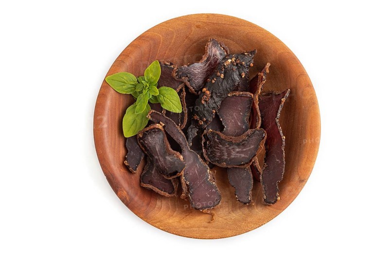 Armenian Basturma dried meat on wooden bowl isolated on white background. Top view, flat lay