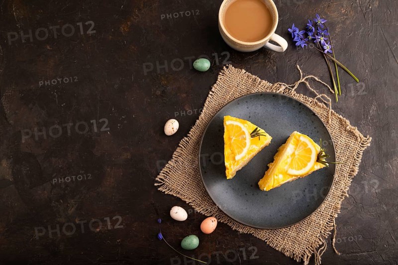 Lemon cake on black concrete background and linen textile, cup of coffee, top view, flat lay, copy space