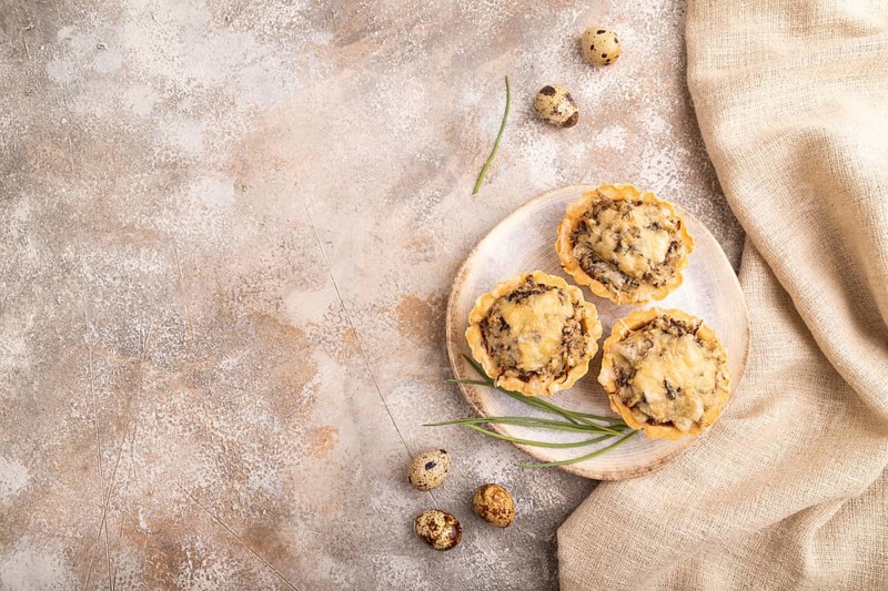 Tartlets with meat and cheese on brown concrete background and linen textile. top view, flat lay, copy space
