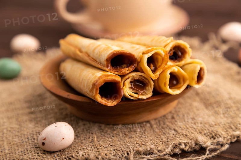 Waffles with caramel on brown wooden background and linen textile, cup of coffee, side view, selective focus