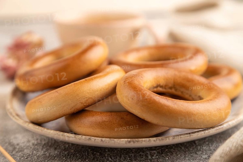 Homemade Ring Bagel with cup of coffee on brown concrete background and linen textile. side view, close up, selective focus