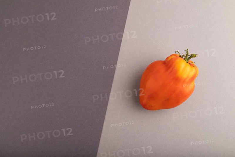 Red Heart Shape tomato on black and gray pastel paper background. Top view, flat lay, copy space. healthy food, vegetable, minimalism