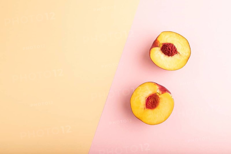 Peach Cut in half on orange and pink paper pastel background. Top view, flat lay, copy space. healthy food, minimalism