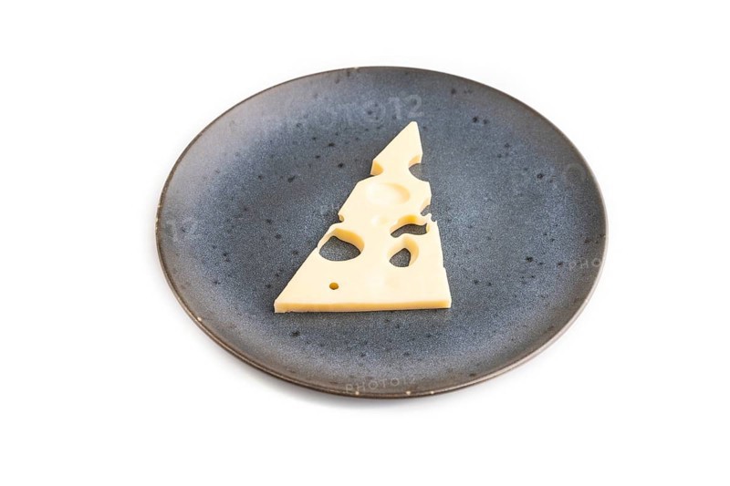 Piece of cheese with holes on blue plate isolated on white background, side view, copy space, minimalism