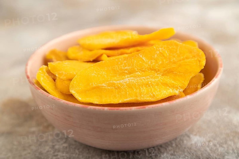 Dried Mango in ceramic bowl on brown concrete background. Side view, close up, selective focus. healthy food, minimalism