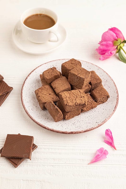 Chocolate marshmallow with cup of coffee on white wooden background. side view, close up