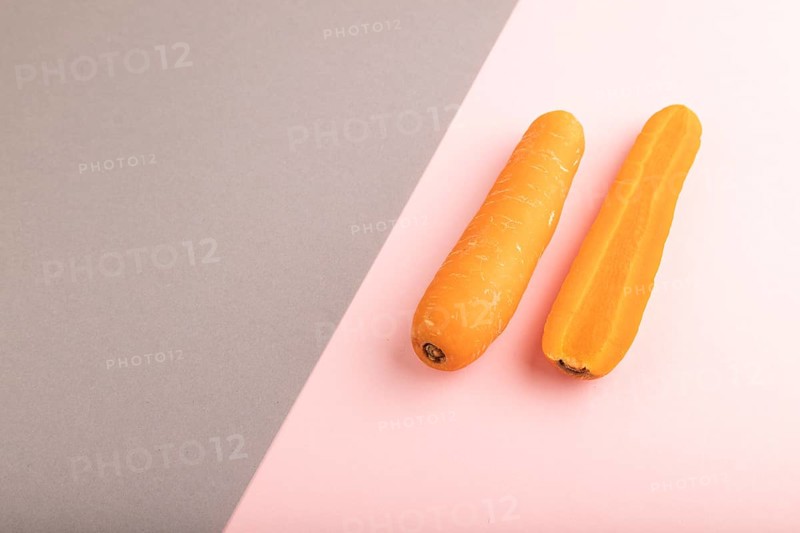 Orange Carrot on gray and pink pastel paper background. Side view, copy space, flat lay. healthy food, vegetable, minimalism