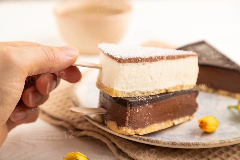 Chocolate and Vanilla Cake pops Marshmallow with hand with cup of coffee on white wooden background and beige linen textile. side view, close up, selective focus hold